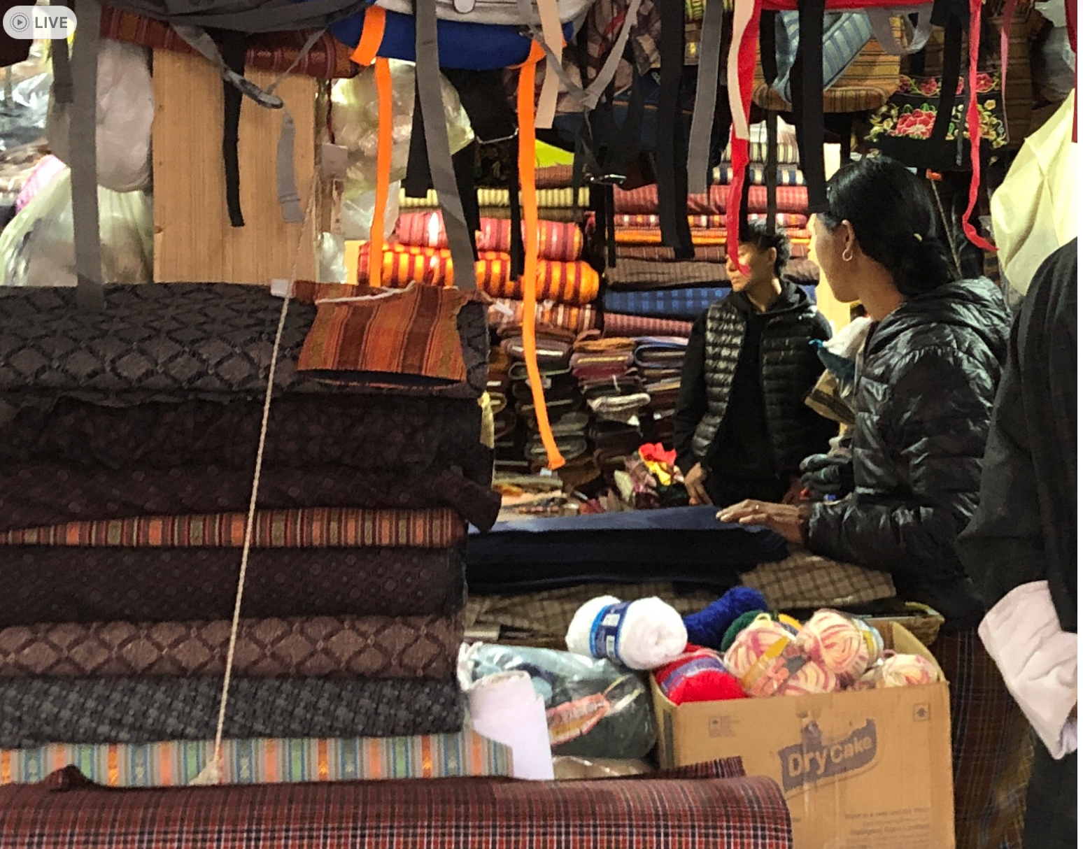Inside Pema's shop with stacks of woven textiles