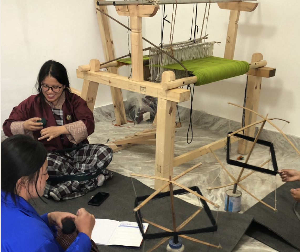 Students working at a traditional wooden weaving loom