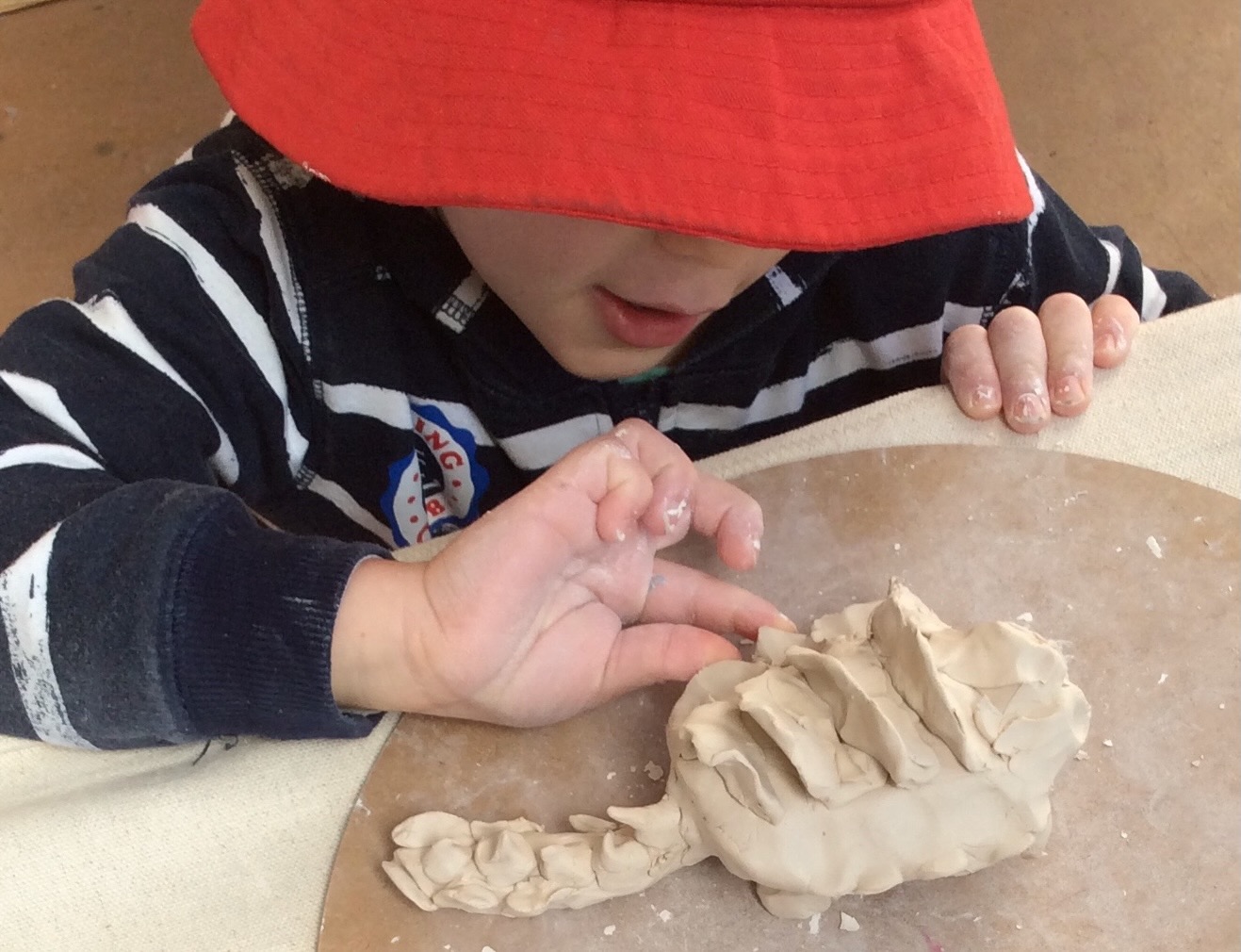 A young child pinching and shaping clay with both hands