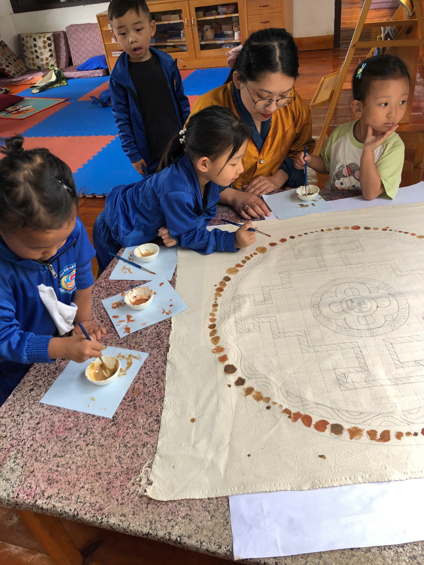 Children painting a mandala with local pigments