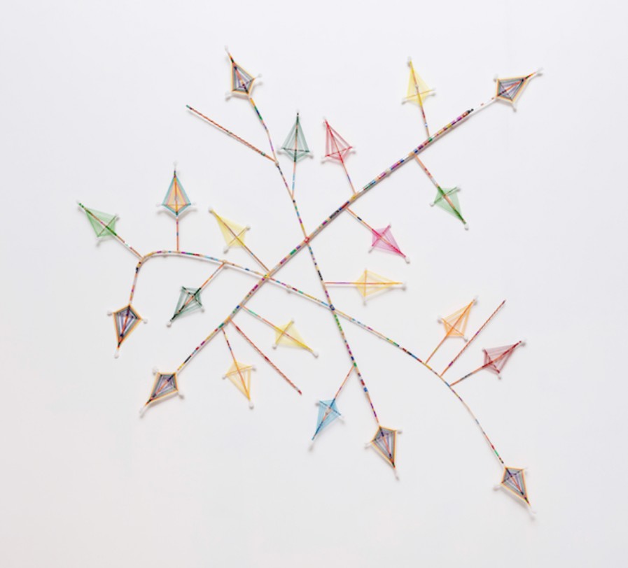 Branching wall sculpture of patterned sticks tipped with small woven thread ornaments